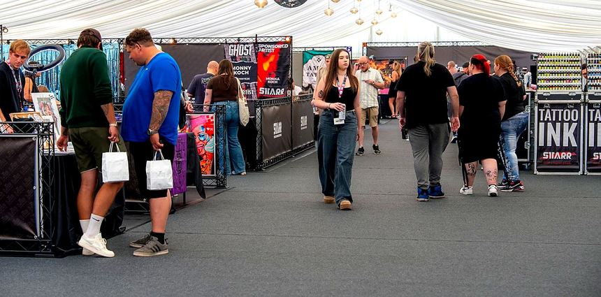Visitors in the aisle of a hall of black-framed stands