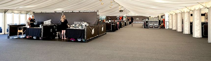 A marquee hall of black-framed exhibition stands built to one standard, photographed before the doors opened